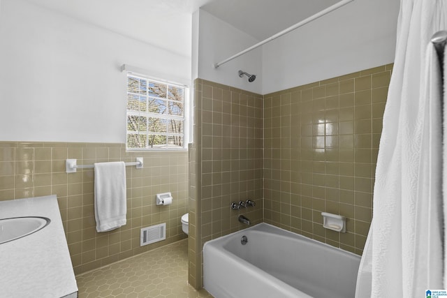 full bathroom featuring toilet, tile patterned flooring, tile walls, shower / bathtub combination with curtain, and vanity