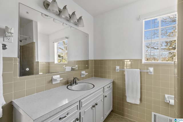 bathroom featuring a healthy amount of sunlight, tile patterned flooring, tile walls, and vanity