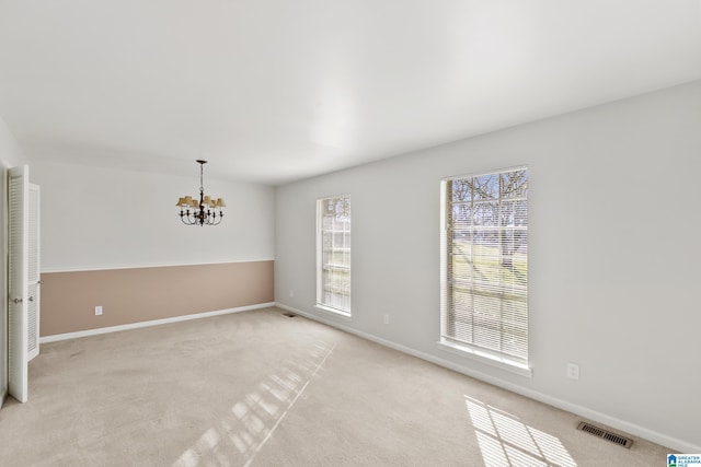 unfurnished room with light carpet and an inviting chandelier