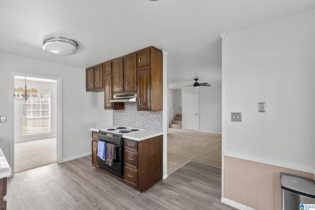 kitchen featuring backsplash, electric range, ceiling fan with notable chandelier, and dark brown cabinetry