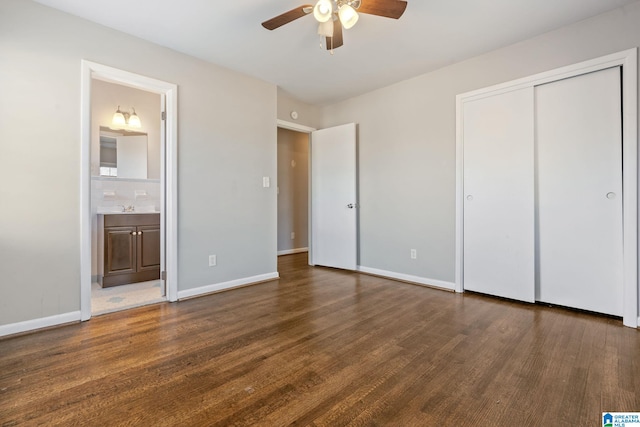 unfurnished bedroom featuring ensuite bath, dark hardwood / wood-style floors, a closet, ceiling fan, and sink