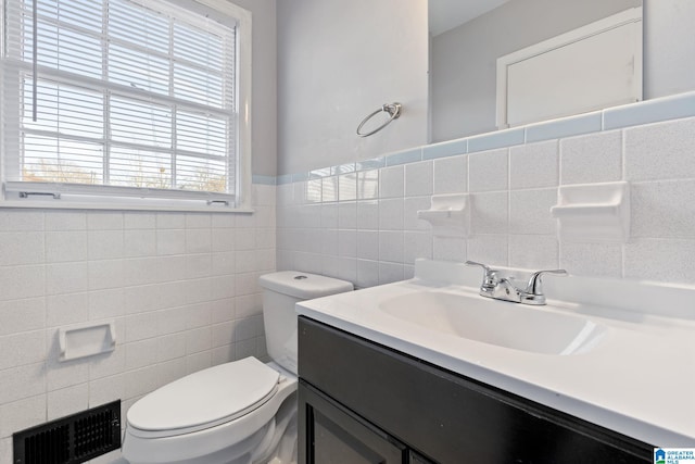 bathroom featuring tile walls, toilet, vanity, and plenty of natural light