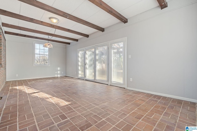 empty room featuring a notable chandelier, french doors, and beamed ceiling