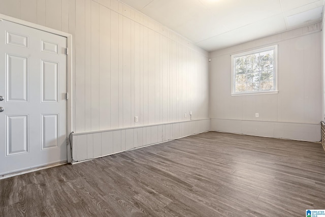 empty room with dark wood-type flooring and wood walls