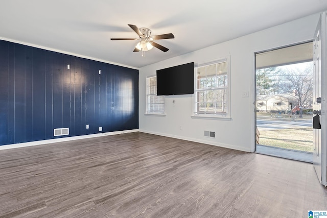 spare room featuring ceiling fan, wooden walls, and wood-type flooring