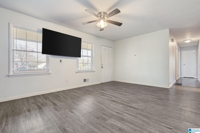 unfurnished living room with ceiling fan, dark wood-type flooring, and plenty of natural light