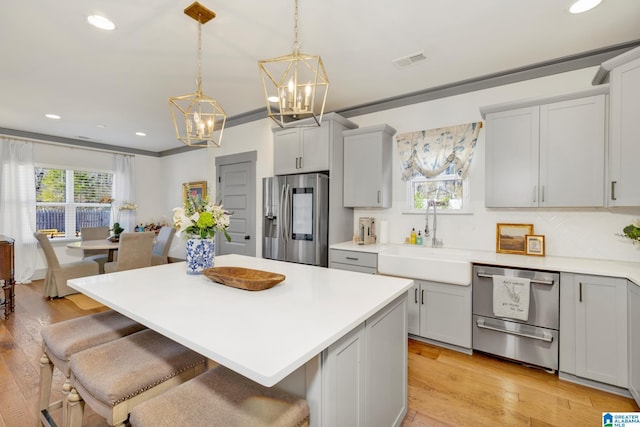 kitchen featuring appliances with stainless steel finishes, decorative backsplash, hanging light fixtures, a kitchen island, and sink