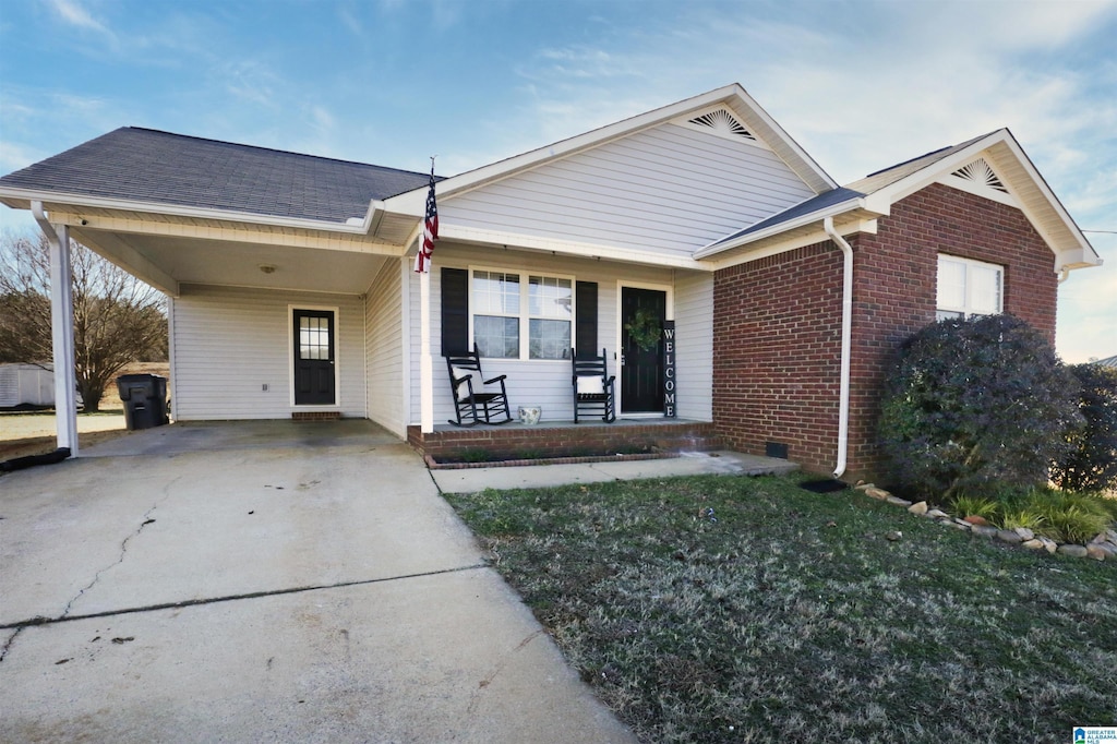 ranch-style home featuring covered porch, a front lawn, and a carport