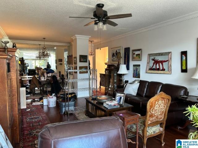 living room featuring ceiling fan with notable chandelier, a textured ceiling, and ornamental molding