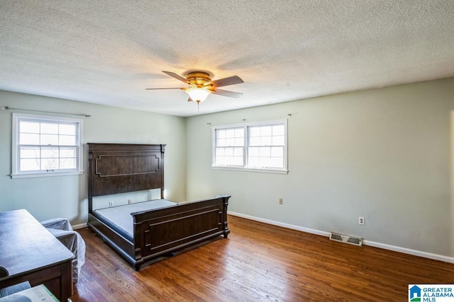 bedroom featuring dark wood-type flooring, ceiling fan, a textured ceiling, and multiple windows