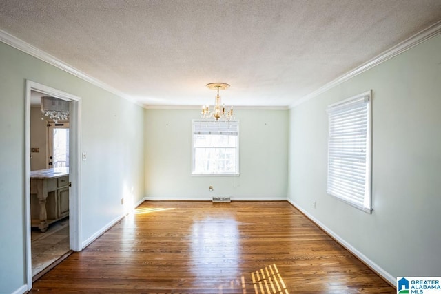 unfurnished room featuring hardwood / wood-style floors, an inviting chandelier, ornamental molding, and plenty of natural light