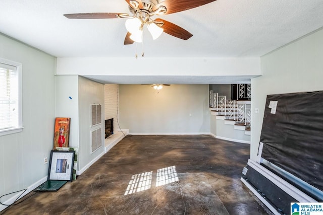 unfurnished living room with ceiling fan, a large fireplace, and a textured ceiling