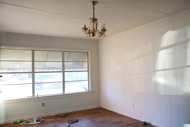 spare room with an inviting chandelier and dark hardwood / wood-style flooring