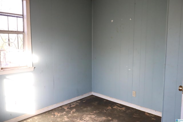 unfurnished room with a wealth of natural light and wooden walls