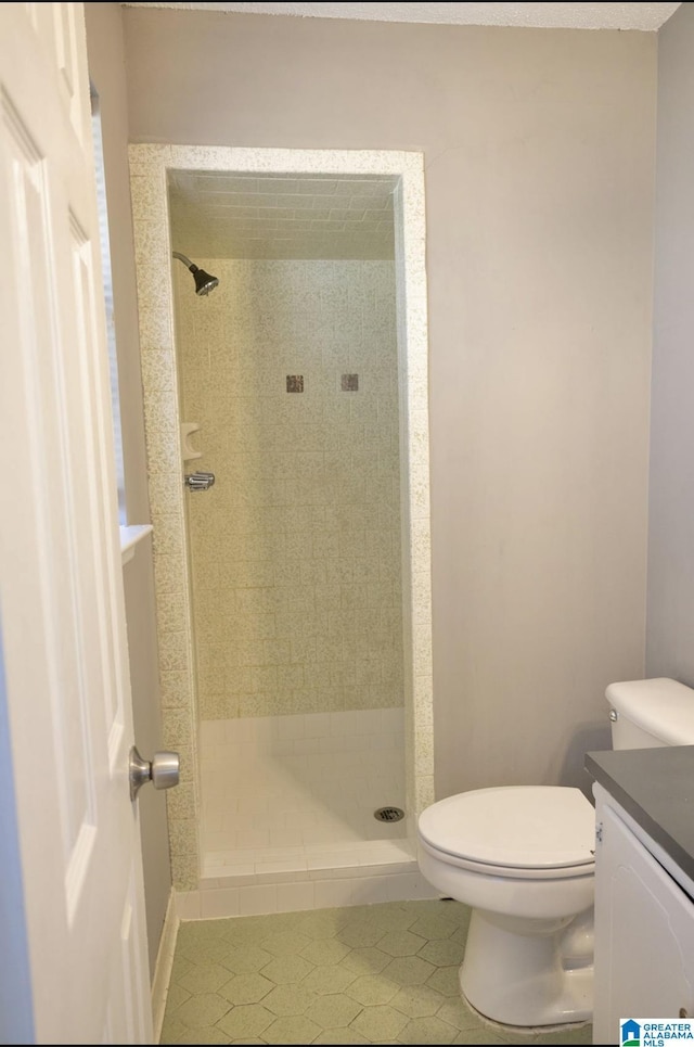 bathroom with toilet, a tile shower, tile patterned floors, and vanity