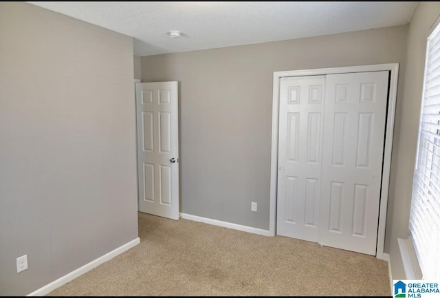 unfurnished bedroom with a closet and light carpet