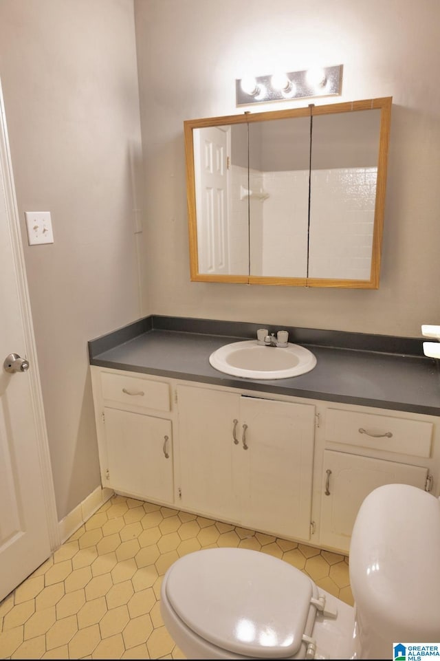 bathroom with toilet, vanity, and tile patterned flooring