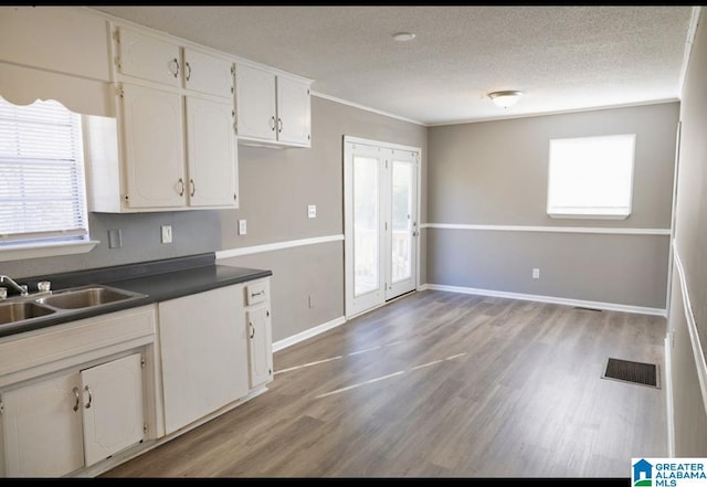 kitchen featuring sink, white cabinets, light hardwood / wood-style flooring, and crown molding