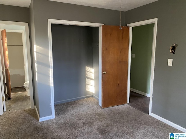 unfurnished bedroom featuring a closet and dark carpet