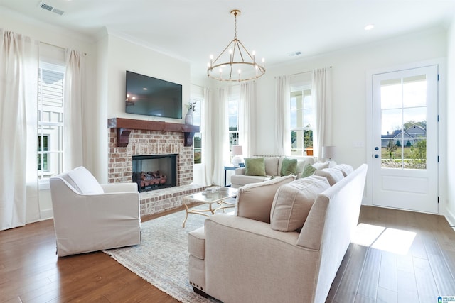 living room with dark wood-type flooring, a fireplace, plenty of natural light, and an inviting chandelier