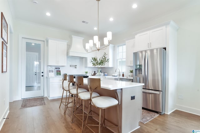 kitchen with stainless steel refrigerator with ice dispenser, white cabinetry, and custom exhaust hood