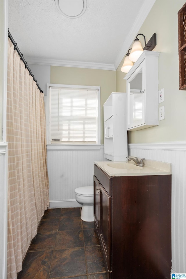 bathroom featuring a textured ceiling, toilet, vanity, and ornamental molding