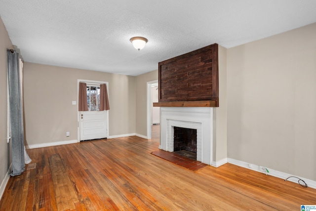 unfurnished living room featuring a textured ceiling, a brick fireplace, and hardwood / wood-style flooring