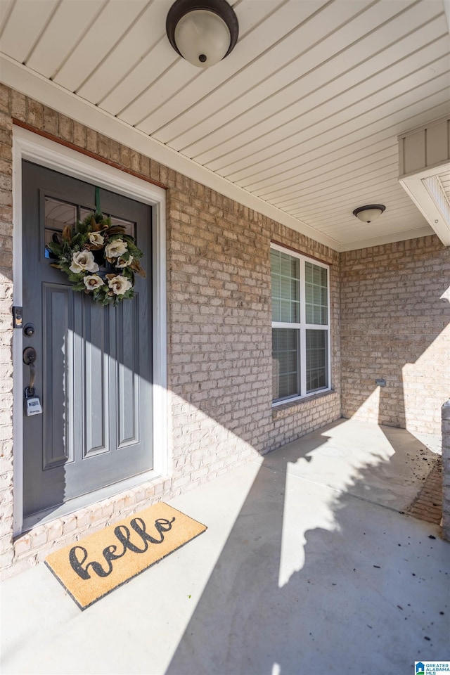 property entrance with covered porch and brick siding