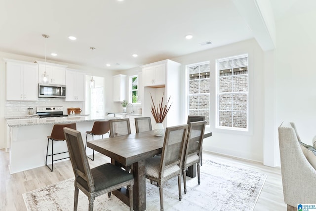 dining area with sink and light hardwood / wood-style floors