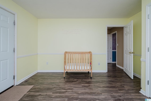 unfurnished bedroom featuring dark hardwood / wood-style floors and a crib