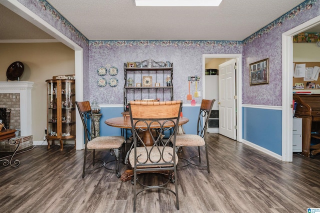 dining space with wood-type flooring, a fireplace, crown molding, and a textured ceiling