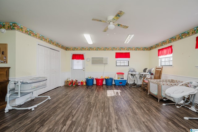 game room featuring a wall unit AC, ceiling fan, and dark hardwood / wood-style flooring