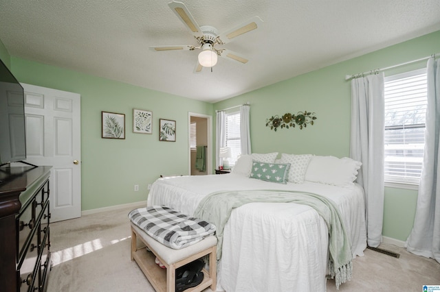 carpeted bedroom with ceiling fan and a textured ceiling