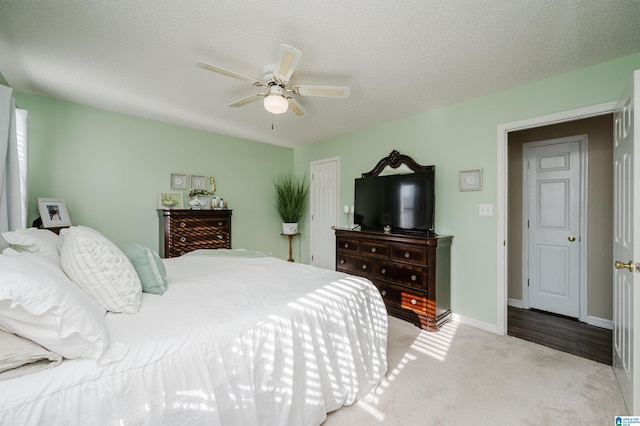 bedroom featuring light carpet, ceiling fan, and a textured ceiling