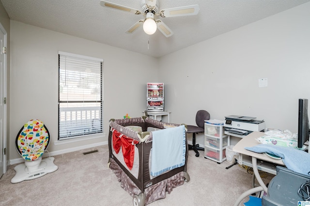 bedroom with ceiling fan, light carpet, and a textured ceiling