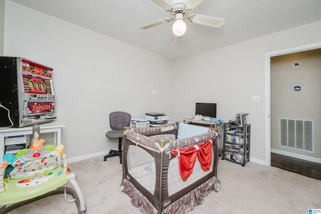 interior space featuring a textured ceiling, ceiling fan, and light colored carpet