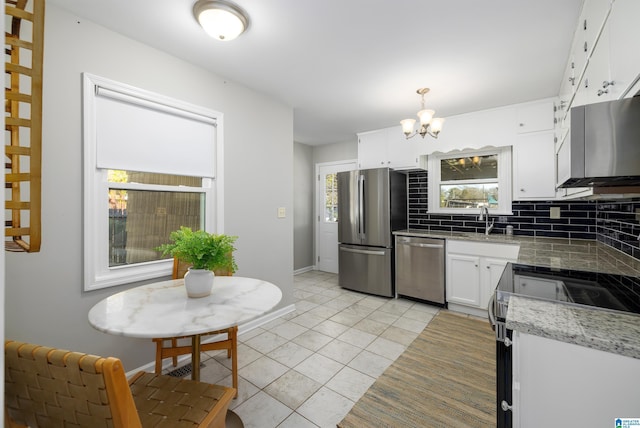 kitchen featuring appliances with stainless steel finishes, sink, white cabinets, light tile patterned flooring, and decorative backsplash