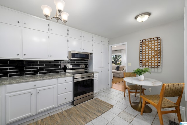 kitchen with appliances with stainless steel finishes, backsplash, white cabinets, light tile patterned floors, and light stone countertops