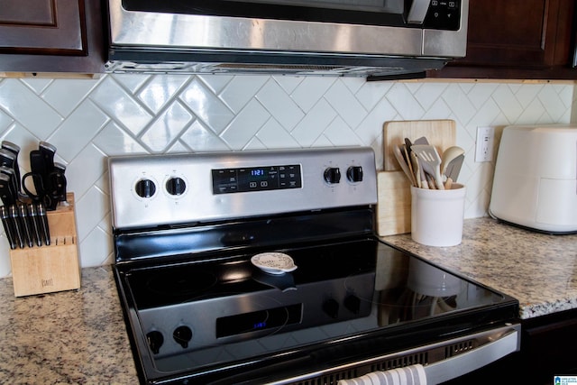 kitchen with dark brown cabinetry, backsplash, light stone countertops, and appliances with stainless steel finishes