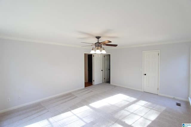 carpeted spare room featuring ceiling fan and crown molding