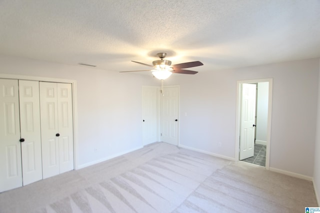 unfurnished bedroom featuring ceiling fan, light colored carpet, and a textured ceiling