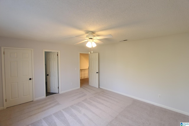 unfurnished bedroom with ceiling fan, light carpet, and a textured ceiling