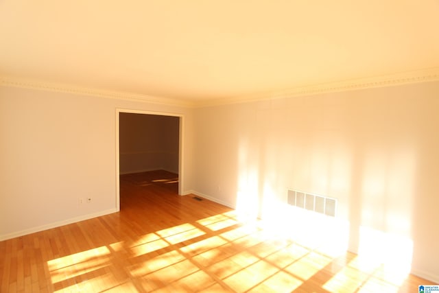 empty room with hardwood / wood-style flooring and ornamental molding