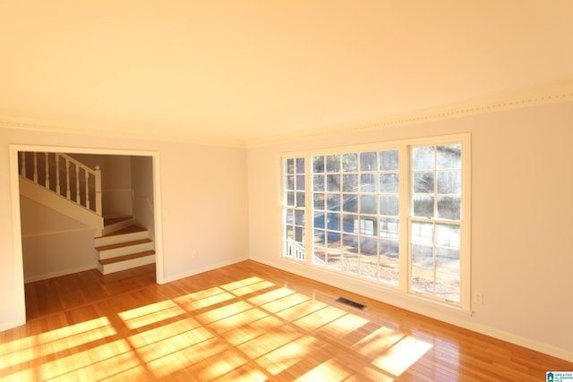 empty room featuring ornamental molding and hardwood / wood-style flooring