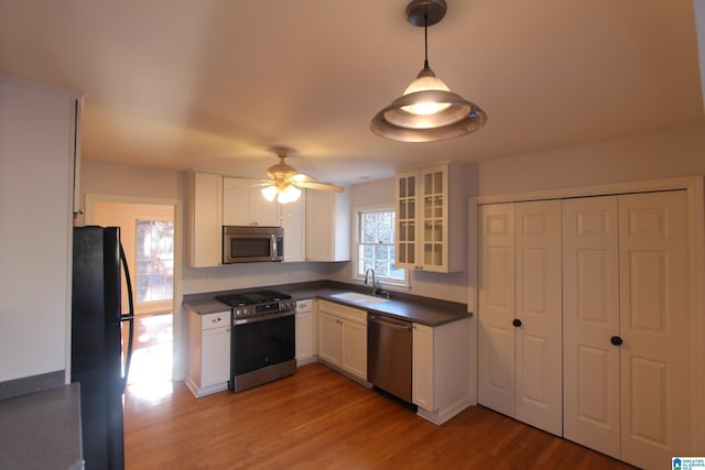 kitchen featuring white cabinetry, ceiling fan, appliances with stainless steel finishes, hanging light fixtures, and sink