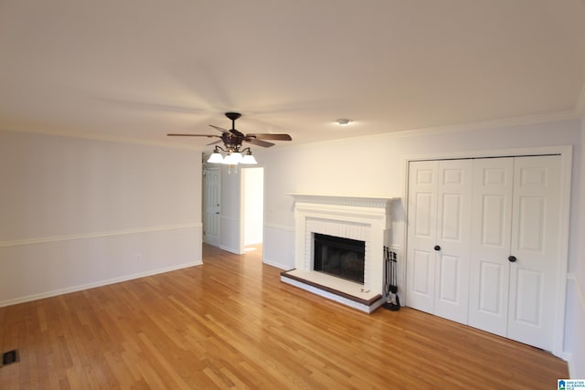 unfurnished living room featuring a brick fireplace, crown molding, light hardwood / wood-style floors, and ceiling fan