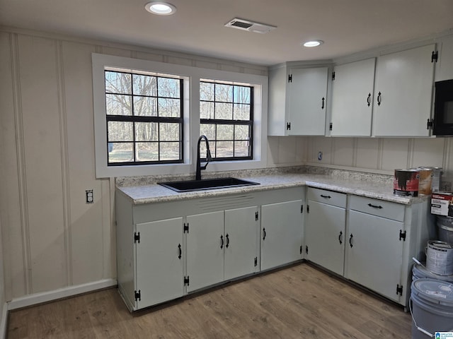 kitchen with sink, white cabinetry, and light hardwood / wood-style flooring