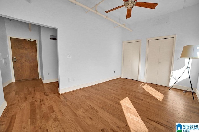 unfurnished bedroom with light wood-type flooring, ceiling fan, and multiple closets