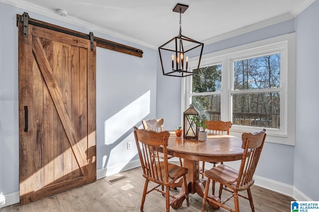 dining space featuring crown molding, a barn door, wood-type flooring, and an inviting chandelier