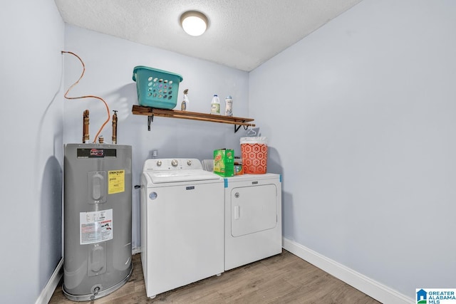 clothes washing area with light wood-type flooring, a textured ceiling, washer and clothes dryer, and electric water heater